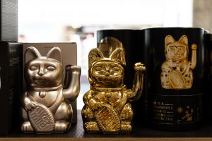 Winkekatzen mit glänzender Oberfläche in Silber und Gold in einer Verkaufsauslage.