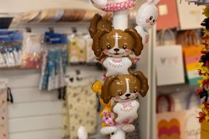 Kleine Tier-Folienballons in Form von braun-weißen Hunden an einem Präsentationsständer.