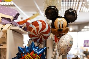 Verschiedene kleine Folienballons an Stäben, darunter ein Motiv der Figur Micky Maus und eine rot-weiß gestreifte Lutscherform.