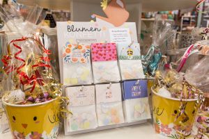 Blumenkonfetti-Aufsteller zwischen aufwendig verpackten Eimern mit Oster-Schokolade