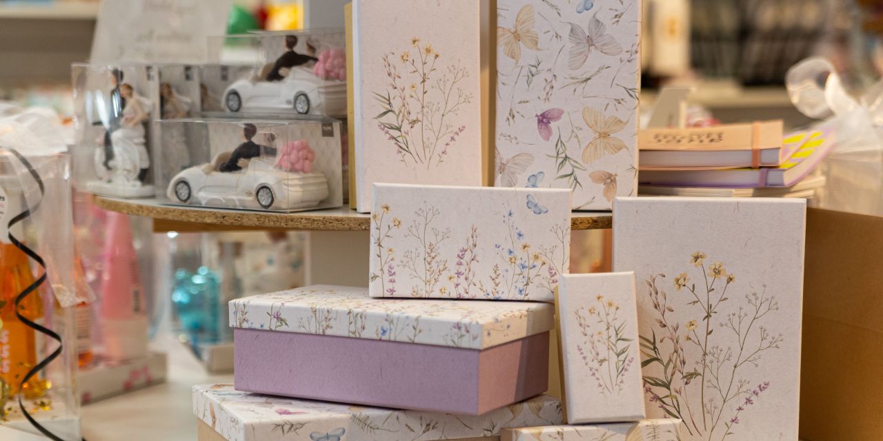 Geschenkboxen in verschiedenen Größen mit Blumen- und Schmetterlingsmustern, neben Hochzeitsfiguren