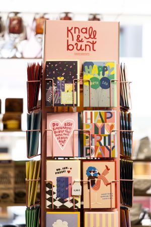 Postkartenständer mit motivierenden und bunten Glückwunschkarten der Marke „Knall & bunt“.