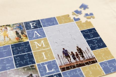 Ein unvollendetes Fotopuzzle mit Motiven einer Familie und dem vertikal geschriebenen Wort „FAMILIE“.