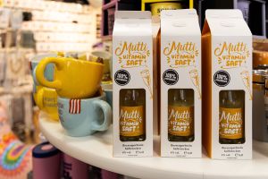 Drei Kartonverpackungen in Milchtüten-Optik mit dem Aufdruck „Mutti VITAMIN SAFT!“ auf einem Verkaufstisch.