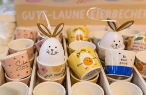 Verschiedene Eierbecher mit heiteren Sprüchen und als Hasen dekorierte Eier