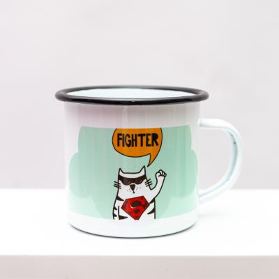 Weiße Emailletasse mit schwarzem Rand. Bedruckt mit dem Motiv einer Katze auf hellgrünem Grund, die ein Superman-Zeichen trägt und „Fighter“ sagt.