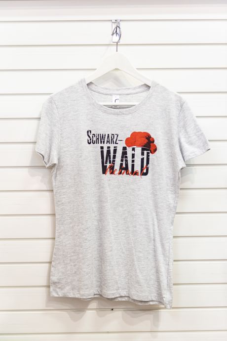 Weiß-graues T-Shirt mit Motiv, bestehend aus serifenlosem, texturiertem, schwarzem Aufdruck „Schwarz-WALD“, traditionellem roten Bollenhut und in roter Schreibschrift gesetzem „heimat“.