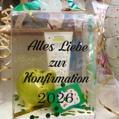 Individuell befüllte, transparente Geschenkbox zur Konfirmation 2026 mit Sparschwein und Pflegeprodukten.