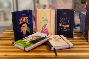 Verschiedene Taschenkalender für 2026 mit illustrierten Einbänden.