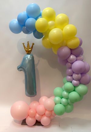 Balloon in the shape of number 1 supported by round balloons in various colors