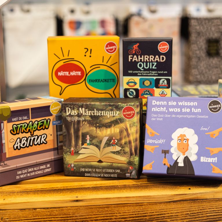 Verschiedene kleine Quiz- und Kartenspiele auf einem Holzdisplay.